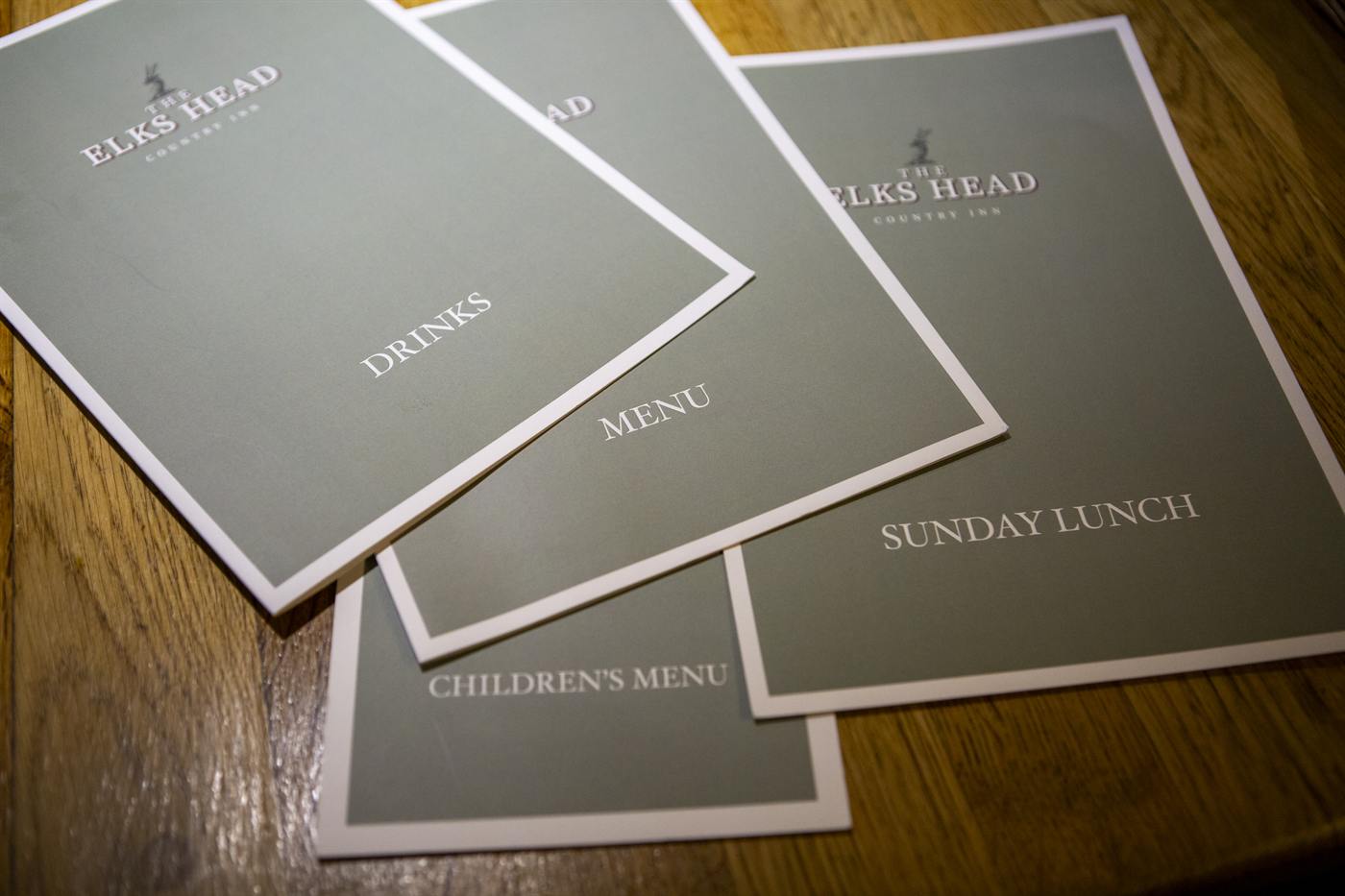 Elks Head drinks, food, Sunday lunch and children's menus on a wooden table