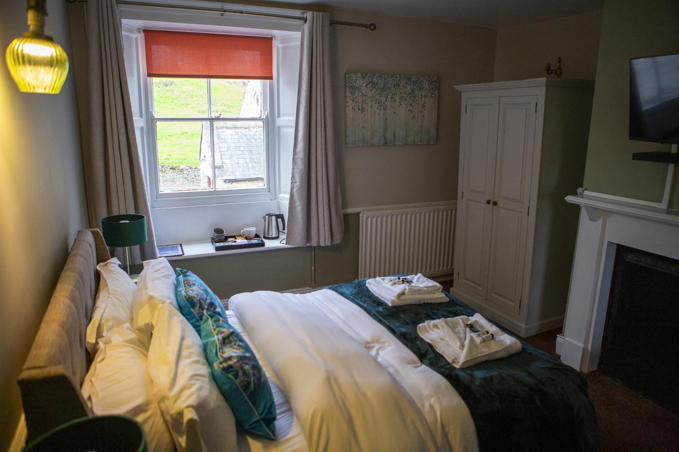 A bedroom with a double bed, fresh towels and a window