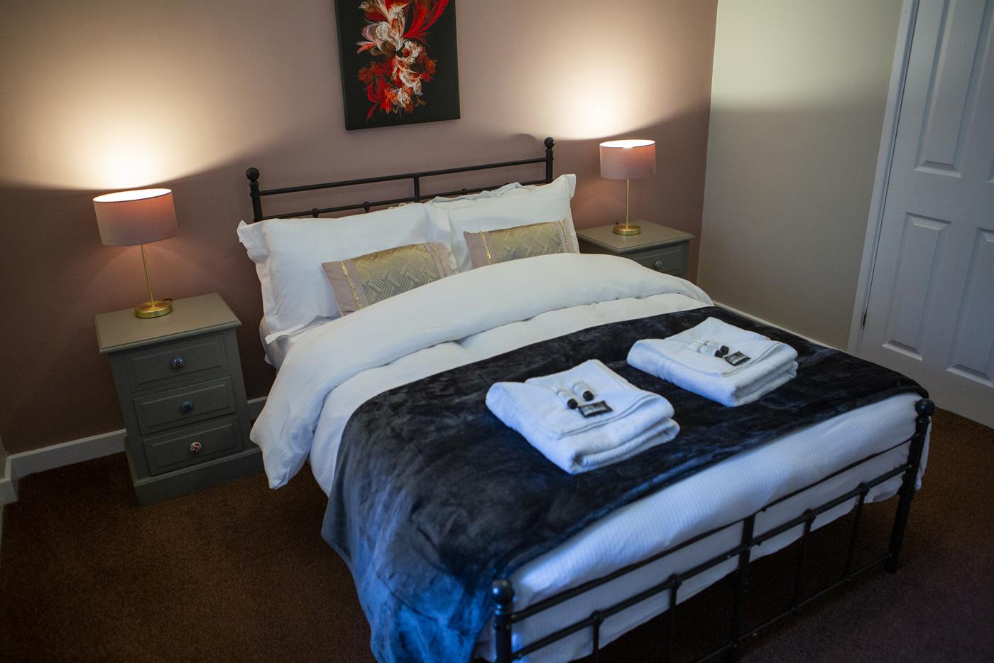 A double bedroom with a black iron bedstead and lamps either side